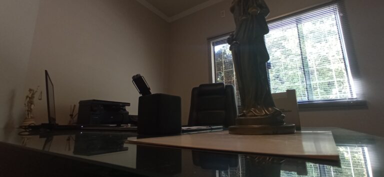 Mesa de trabalho do escritório Blasco Advogados, em Pelotas, com estátua da Justiça